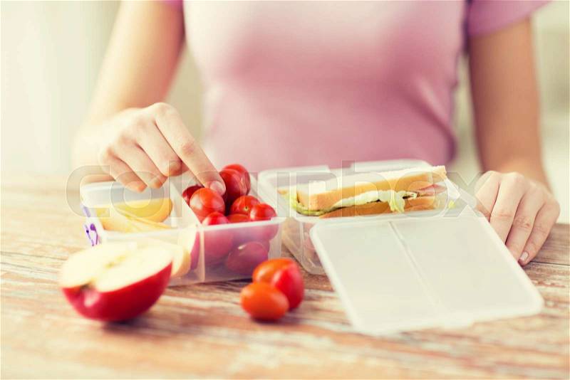 Healthy eating, storage, dieting and people concept - close up of woman with food in plastic container at home kitchen, stock photo