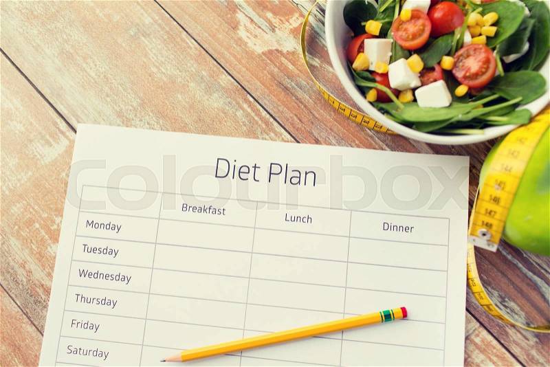 Healthy eating, dieting, slimming and weigh loss concept - close up of diet plan paper green apple, measuring tape and salad, stock photo