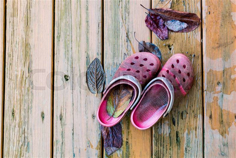 Pair of old dirty red garden shoes on wooden deck floor, stock photo