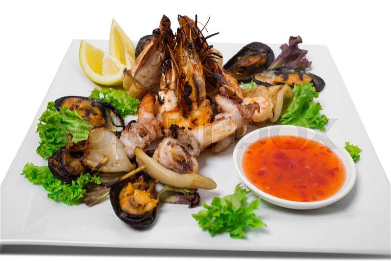 Delicious grilled seafood platter with hot sauce. Isolated on a white background, stock photo