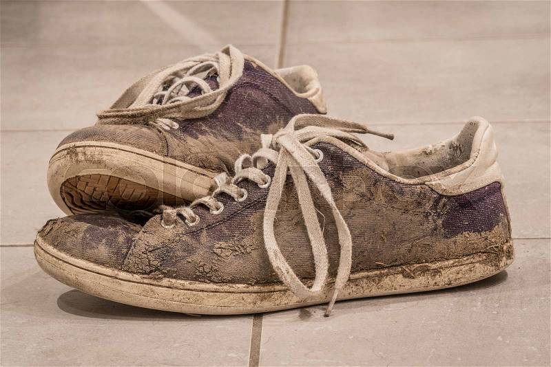 Dirty shoes with mud and soil on a floor, stock photo