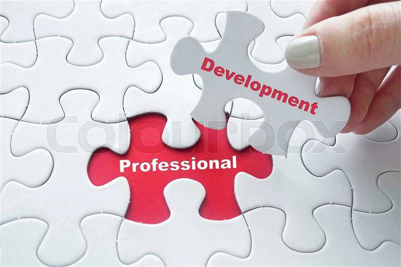 Close up of girl's hand placing the last jigsaw puzzle piece with word Professional Development as studying concept, stock photo
