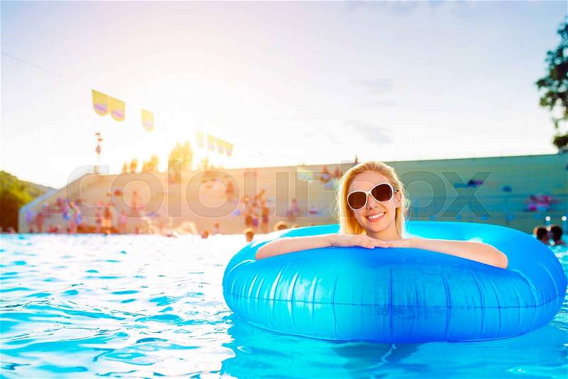 Woman in inflatable ring in swimming pool. Sunny summer, heat and water, stock photo