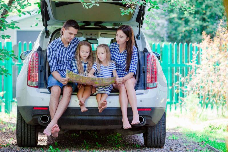 Family with two kids looking at map while traveling by car, stock photo