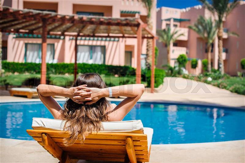 Woman lying on a lounger by the pool at the hotel, stock photo
