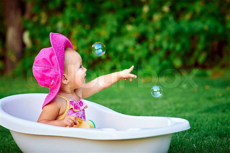 Little girl in a red hat bathed in the bath, stock photo