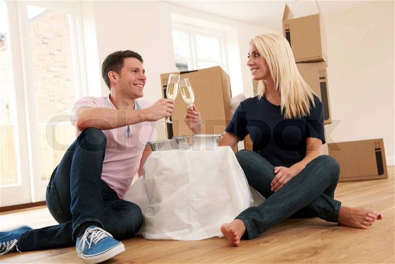 Couple Celebrating Moving Into New Home With Champagne And Takeaway Meal, stock photo