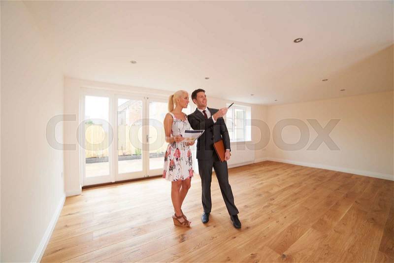 Estate Agent Showing Young Woman Around New Empty Property, stock photo