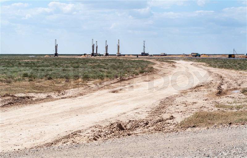 Looking across flat arid remote terrain to an operative drilling rig in Central Asia, stock photo