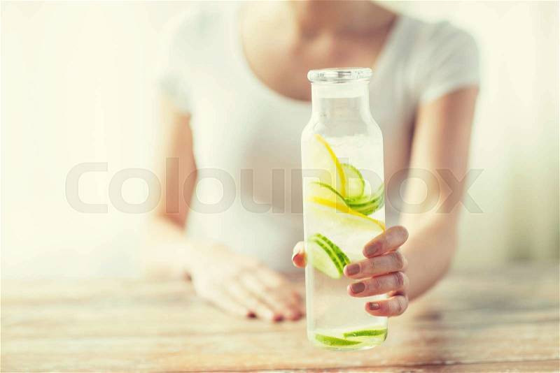 Healthy eating, drinks, diet, detox and people concept - close up of woman with fruit water in glass bottle, stock photo