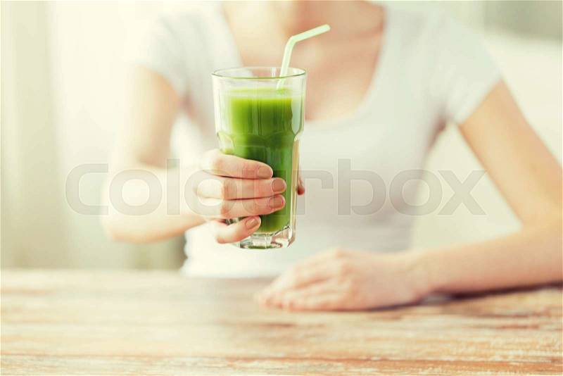 Healthy eating, food, diet, detox and people concept - close up of woman hands with green juice on wooden table, stock photo