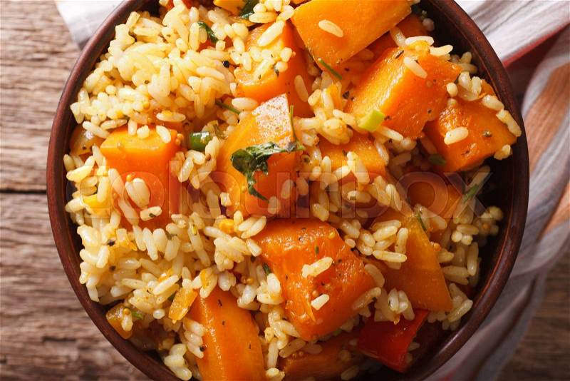 Vegetarian food: rice with pumpkin in a bowl close-up on the table. Horizontal view from above , stock photo
