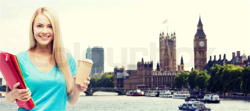 Education, school, study abroad, drinks and people concept - smiling student girl with folders and cup of coffee over london city background, stock photo