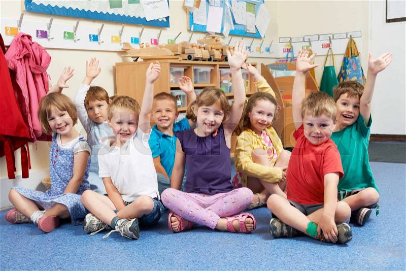 Group Of Elementary School Pupils Putting Hands Up In Class, stock photo