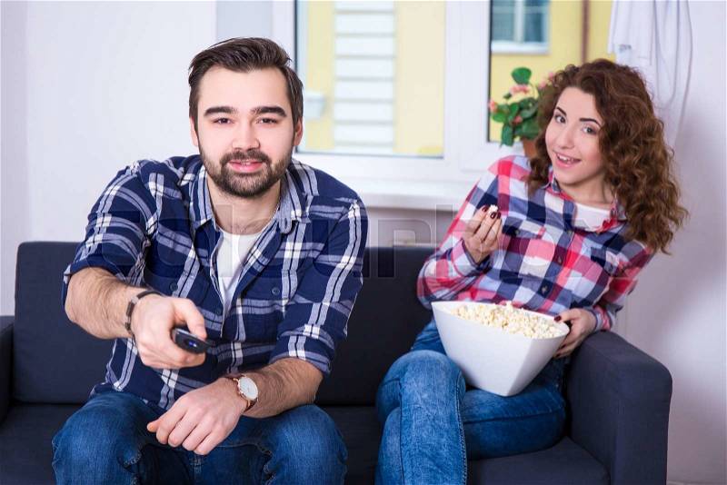 Young beautiful couple with popcorn watching tv or movie, stock photo