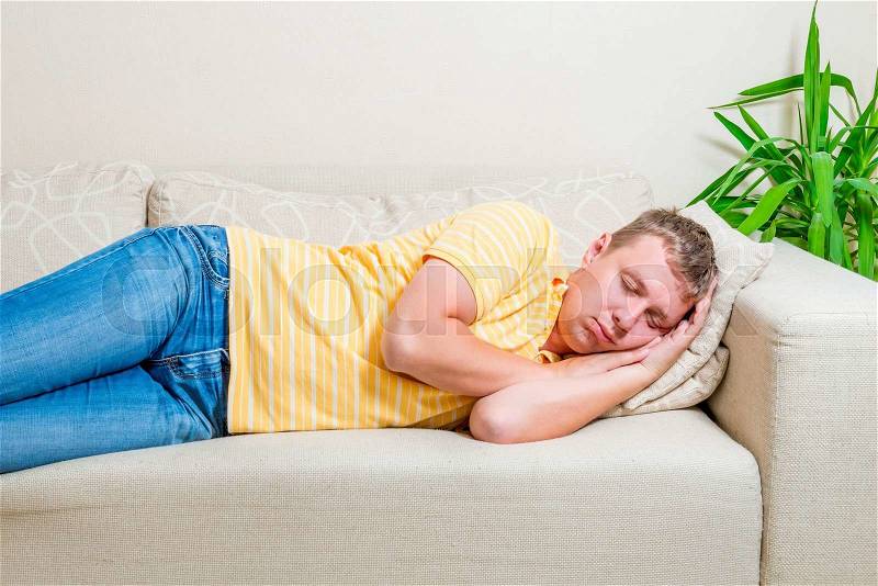 Tired man lay down to take a nap on the sofa in the living room, stock photo