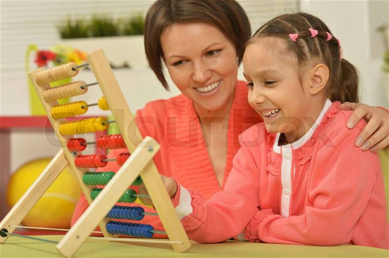 Little girl doing math exercises with her mother at home, stock photo