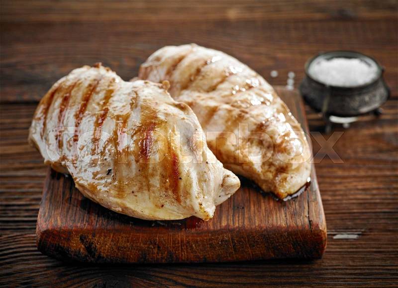 Grilled chicken fillets on wooden cutting board, stock photo