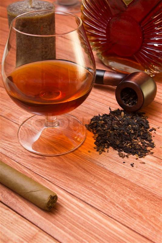 Cognac in glass and tobacco pipe on a wooden surface, stock photo