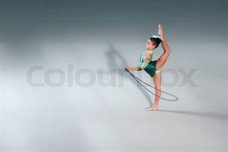 Gymnast in a beautiful green costume performs exercises with a skipping rope, stock photo