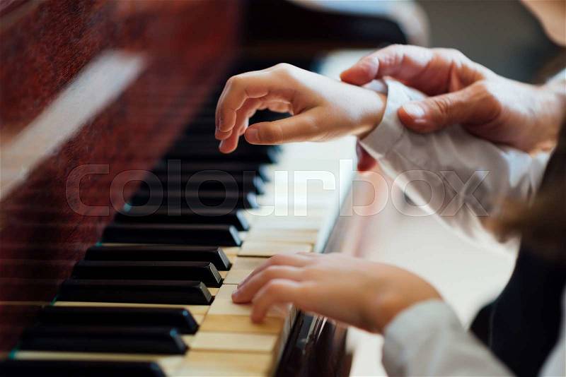 Experienced master piano hand helps the student, close-up, stock photo