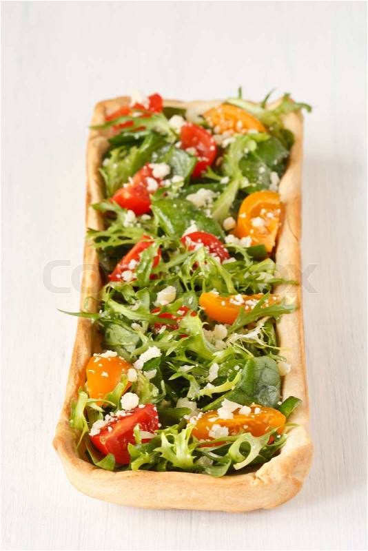 Homemade pie with green salad, cherry tomatoes and parmesan on a white wooden board, stock photo