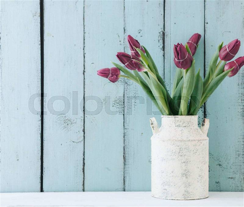 Bouquet of tulip flowers in vintage vase on the shelf over blue wooden background, shabby chic interior decor, stock photo
