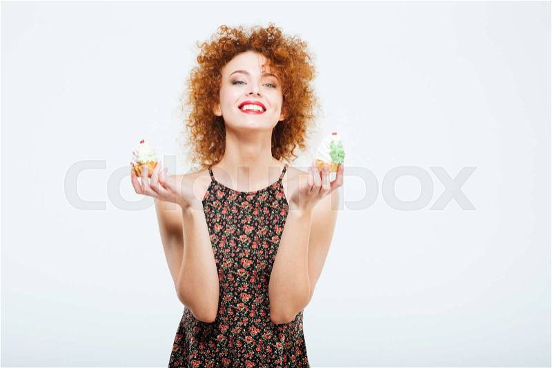Happy redhead woman holding cakes isolated on a white background and looking at camera, stock photo