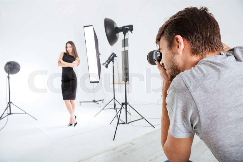 Photographer working with model in studio with softboxes, stock photo