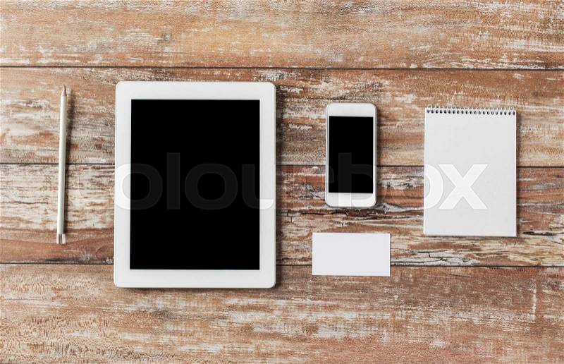 Business, education, objects and technology concept - close up of notebook, tablet pc computer and smartphone on table, stock photo