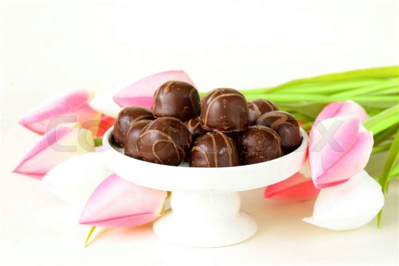 Chocolate candy and flowers on wooden background, stock photo