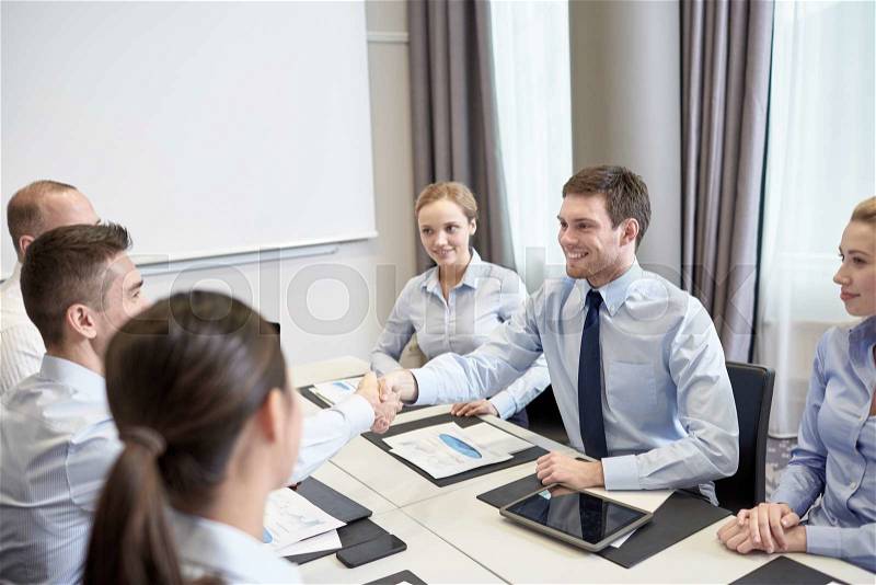 Business, people, partnership, gesture and startup concept - group of smiling business people meeting and shaking hands in office, stock photo