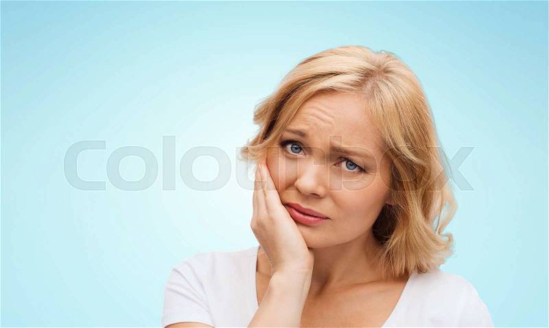 People, healthcare, dentistry and problem concept - unhappy woman suffering toothache over blue background, stock photo