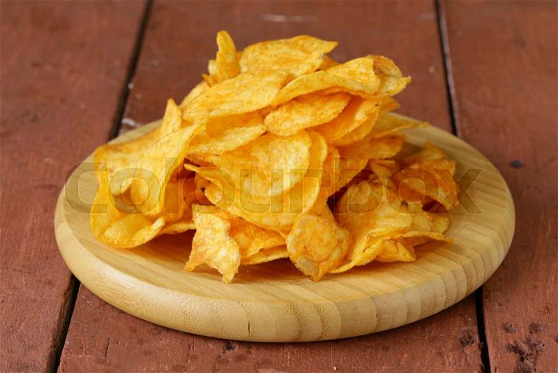 Natural potato chips with paprika on a wooden table, stock photo