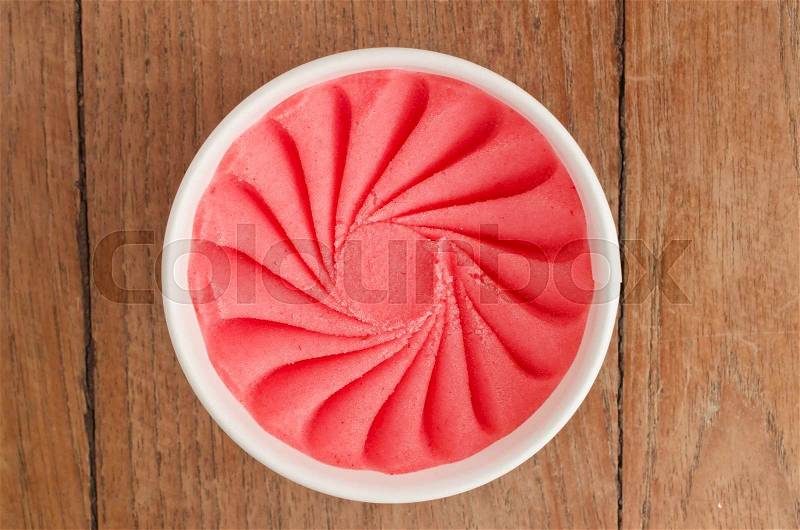 Overhead view of homemade Strawberry Italian ice cream tub on wooden background, stock photo