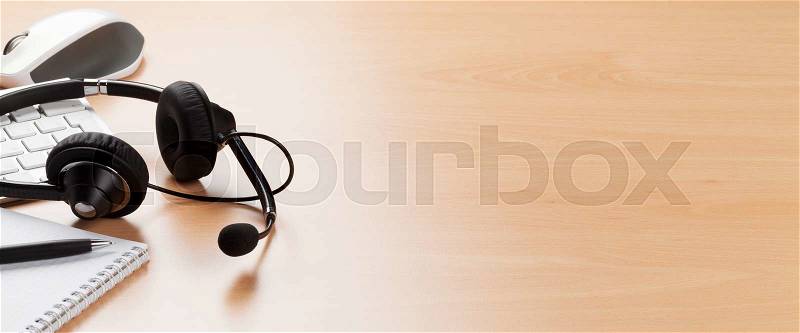 Office desk with headset laying on keyboard. Call center table. View with copy space, stock photo