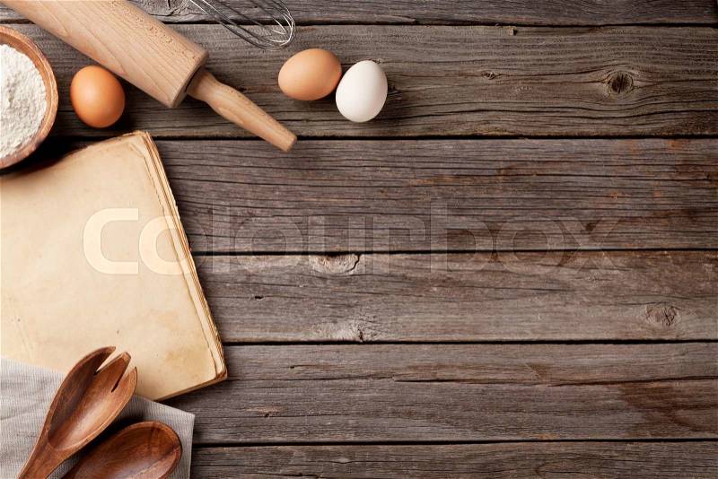 Kitchen table with blank vintage recipe cooking book, utensils and ingredients. Top view with copy space, stock photo