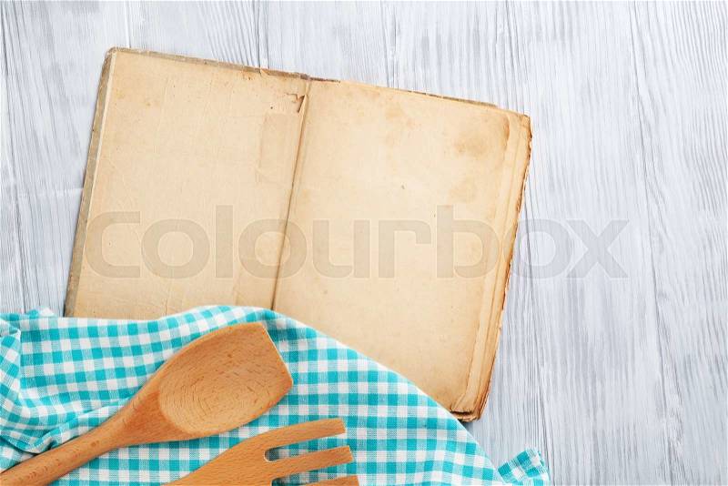 Kitchen table with blank vintage recipe cooking book and utensils. Top view with copy space, stock photo