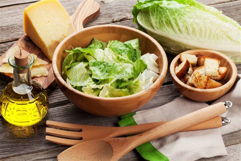 Fresh healthy caesar salad cooking on wooden table, stock photo