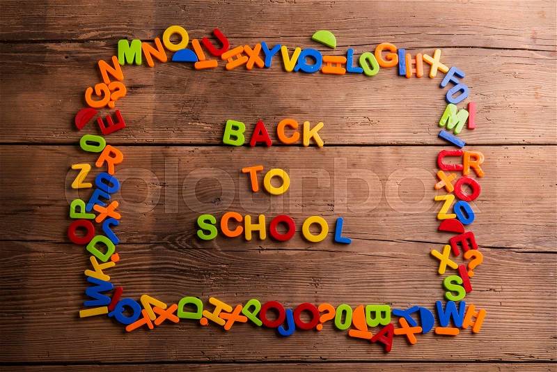 Colorful plastic letters and numbers against wooden background, frame composition, stock photo