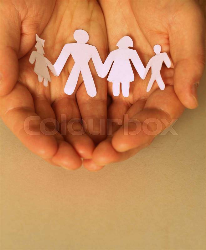 Male hands holding a paper human family, stock photo