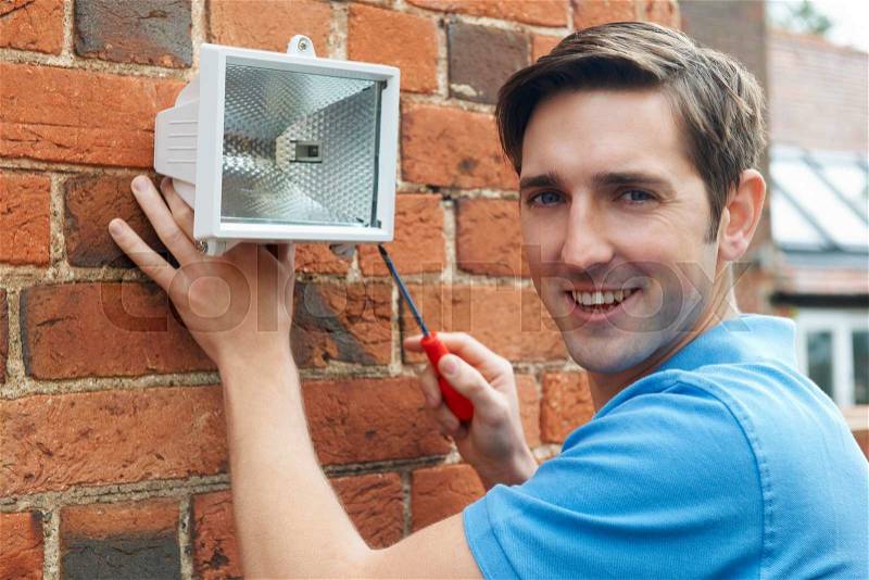 Man Fitting Security Light To House Wall, stock photo