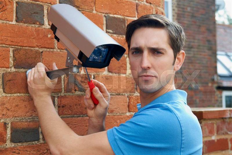 Man Fitting Security Camera To House, stock photo