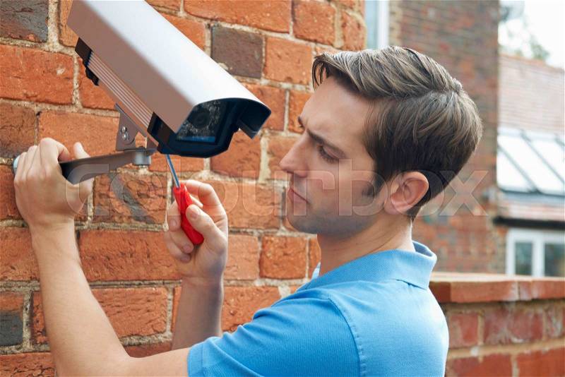 Man Fitting Security Camera To House Wall, stock photo