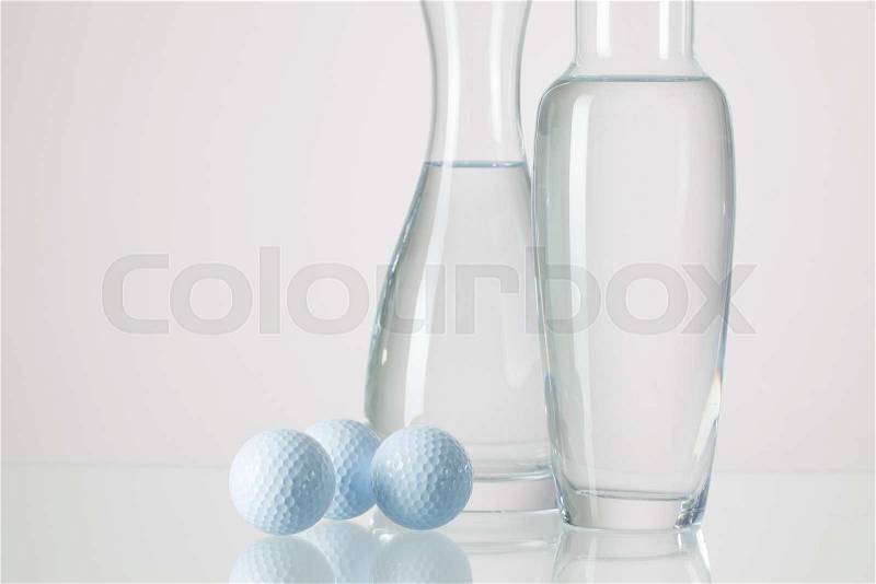 Two vases with clean water and golf balls on a glass table, stock photo
