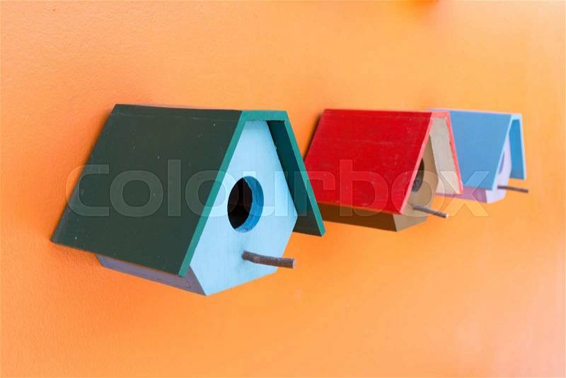Colorful bird nest wood box decorated on orange wall background, stock photo