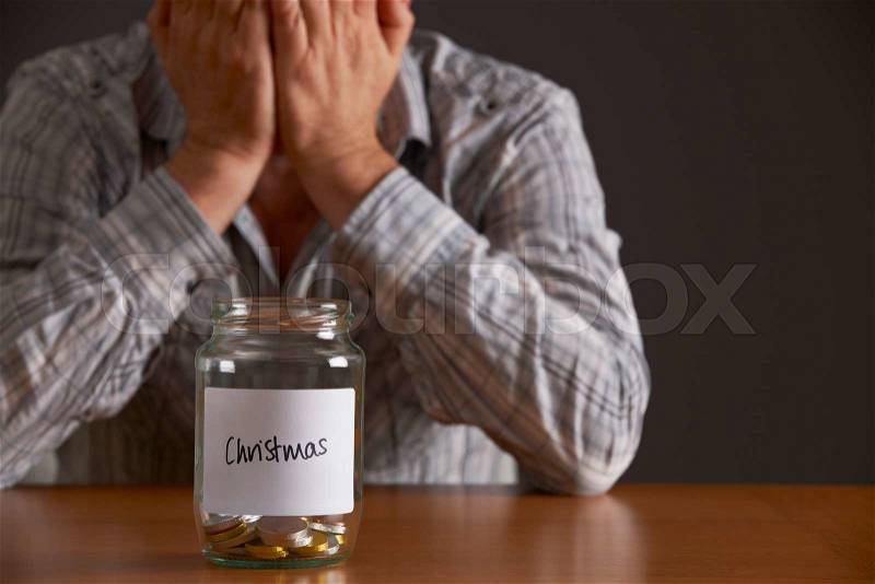Man With Head In Hands Looking At Jar Labelled Christmas, stock photo