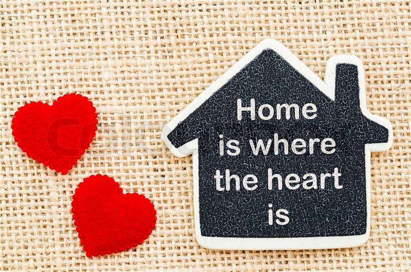 Home is where the heart is word in wooden home model with red heart on sack background, stock photo