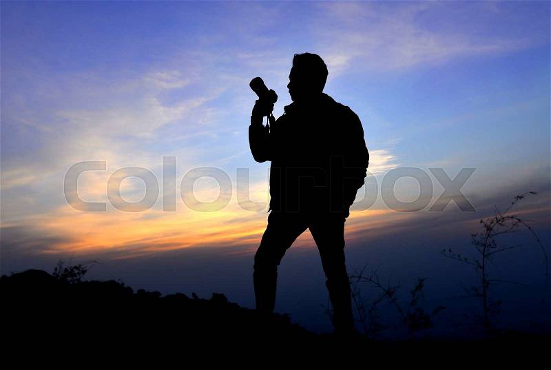 Silhouette of freedom photographer action with camera in sun set time on the mountain view, stock photo