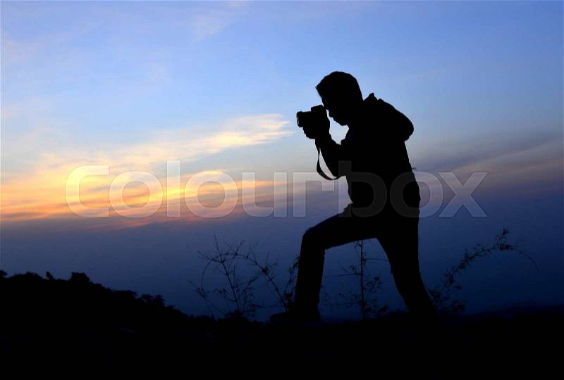 Silhouette of freedom photographer action with camera in sun set time on the mountain view, stock photo